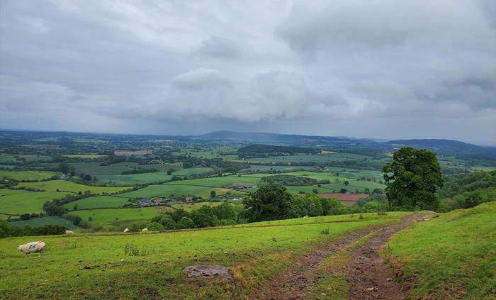 Looking over the mountain range, with fields in landscape and farm path going off to the right